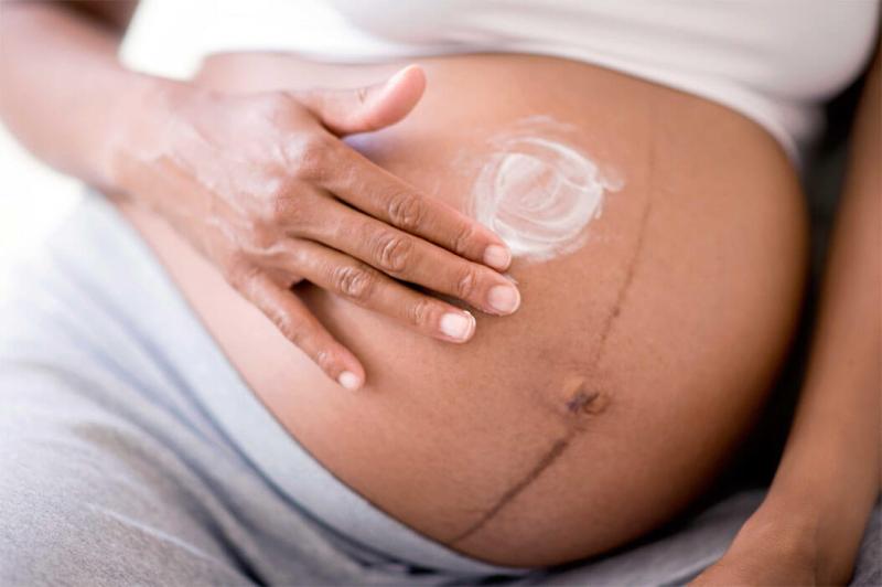 Нанесение крема на живот у беременной